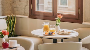 A breakfast setting with a table, chairs, and a window view. - Rimon Place-Kosher (Venice)