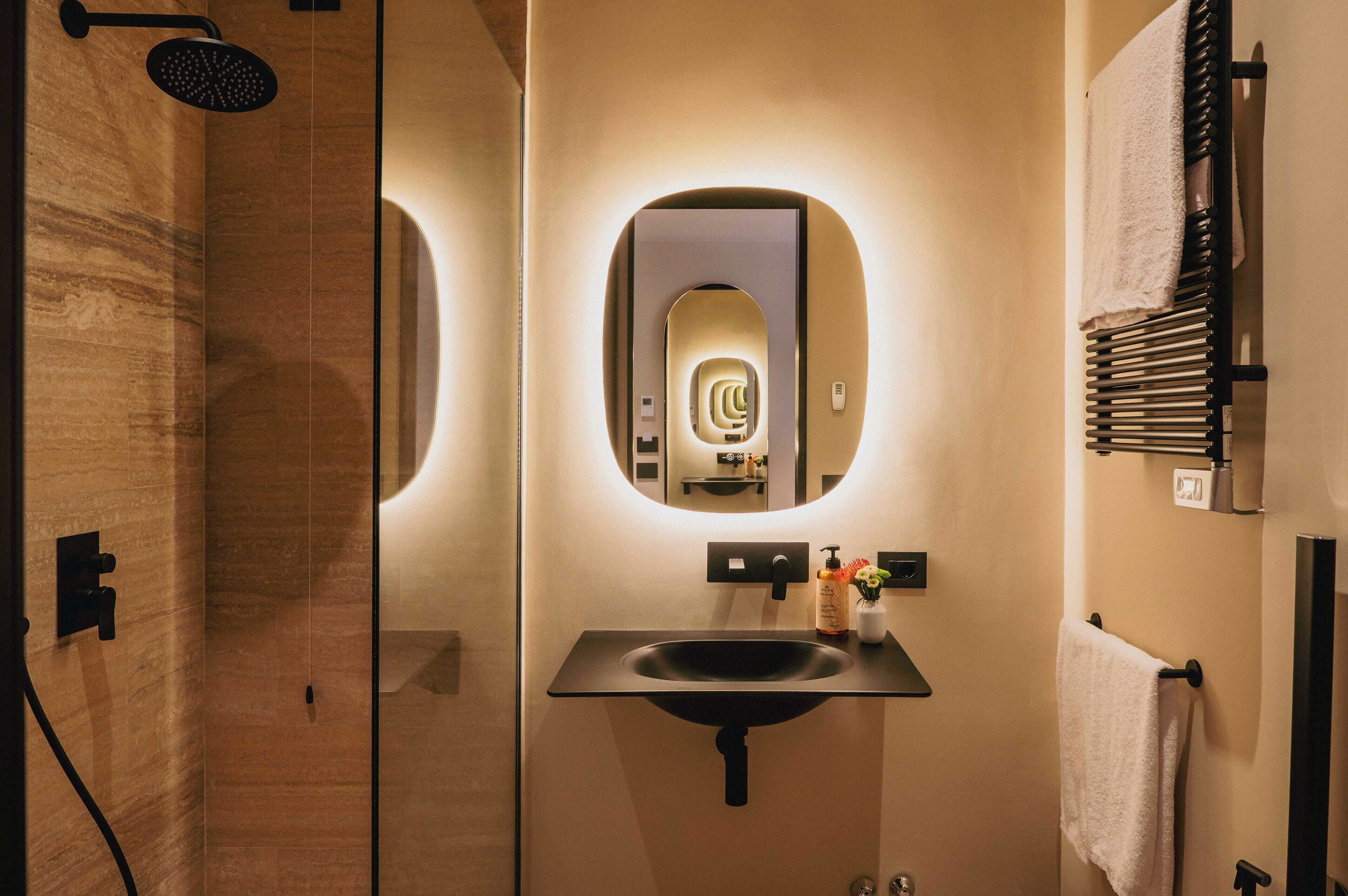 A modern bathroom with a large mirror, a sink, and a towel rack.