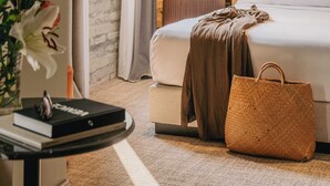 A hotel room with a bed, bedside table, lamp, and a view of the outdoors through a window. - Rimon Place-Kosher (Venice)