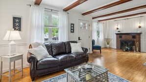 A living room with a leather sofa, a glass coffee table, and a fireplace. - Coastal Comfort With Stunning Harbor Views 3 Bedroom Home (Plymouth)