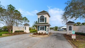 A gated entrance with a small tower-like structure, a sign indicating a private property, and a clear sky. - 225 Seahorse Way 3 Bedroom Home (Panama City Beach)