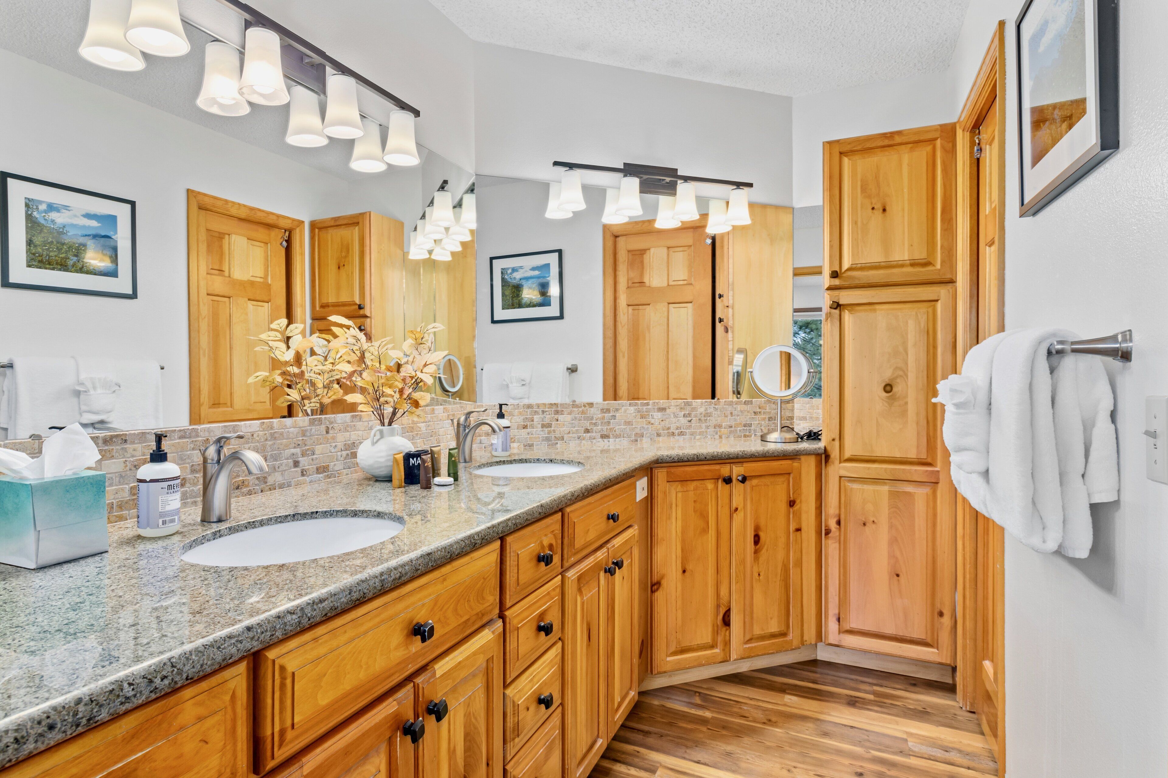 A modern bathroom with two sinks, wooden cabinets, and a large mirror.