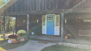 Una cabaña rústica con una puerta azul, un porche de madera y un letrero que dice "ON CABIN".