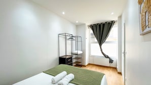 A bedroom with a bed, a hanging chair, and a window with curtains.