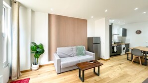 A modern living room with a grey sofa, a wooden coffee table, and a potted plant.