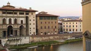 A historic building with a river in front, featuring a prominent archway and a bridge. - LunArt (Florence)