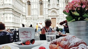 A dining table with a croissant, a cup labeled "Opera Caffè", and a dessert with a strawberry. - LunArt (Florence)