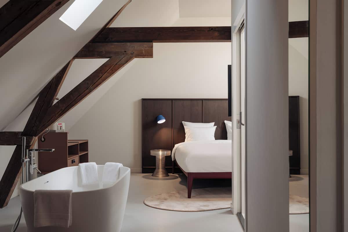 A modern bathroom with a freestanding bathtub, a wooden ceiling, and a white sink.