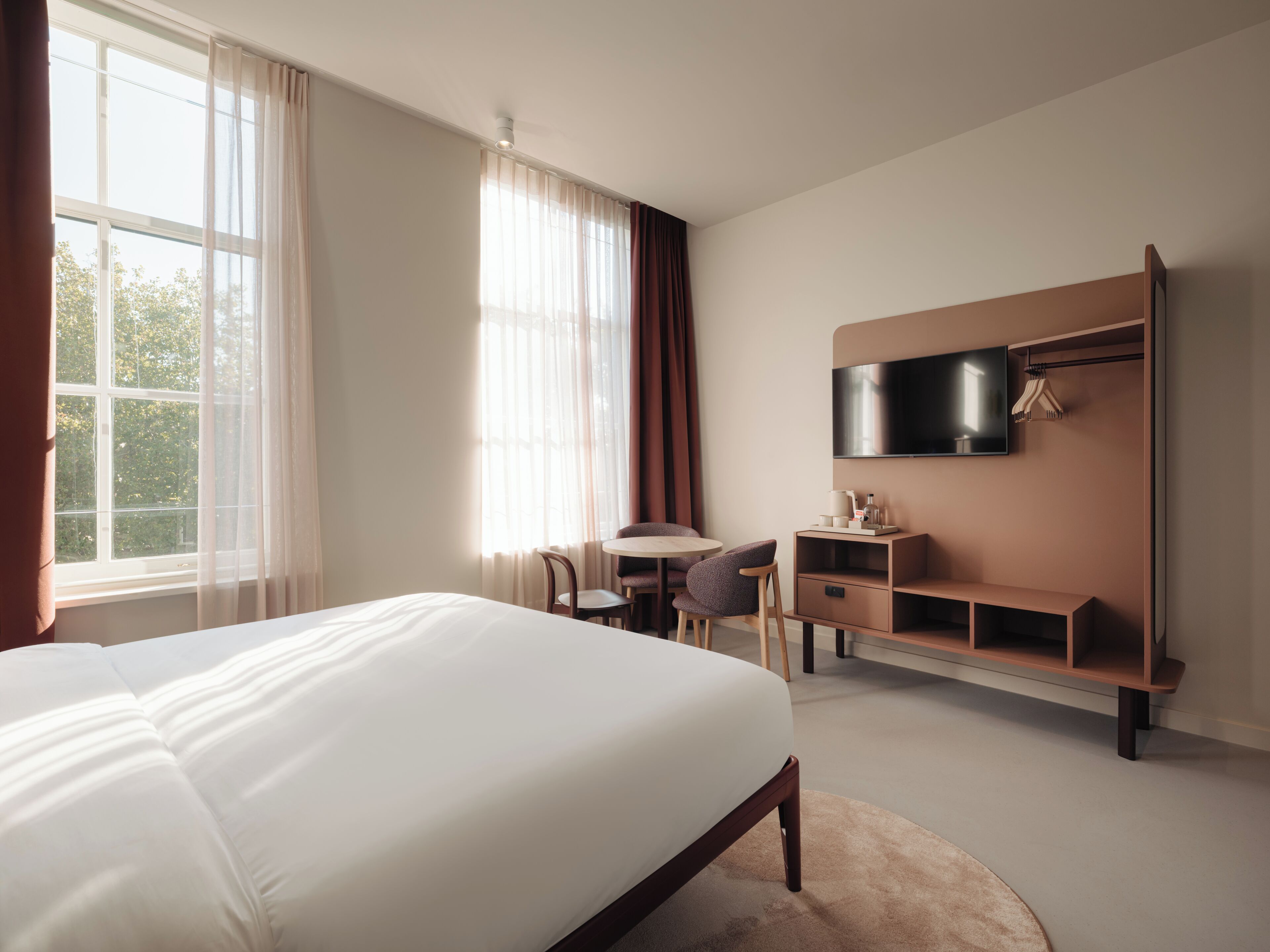 Une chambre d’hôtel avec un grand lit, un bureau, une chaise, une télévision et une armoire.