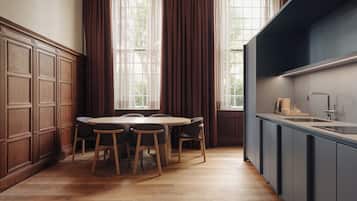 A modern kitchen with wooden cabinets, a dining table with chairs, and a large window with curtains.