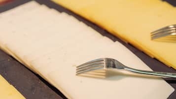 A tray with sliced cheese and two forks.
