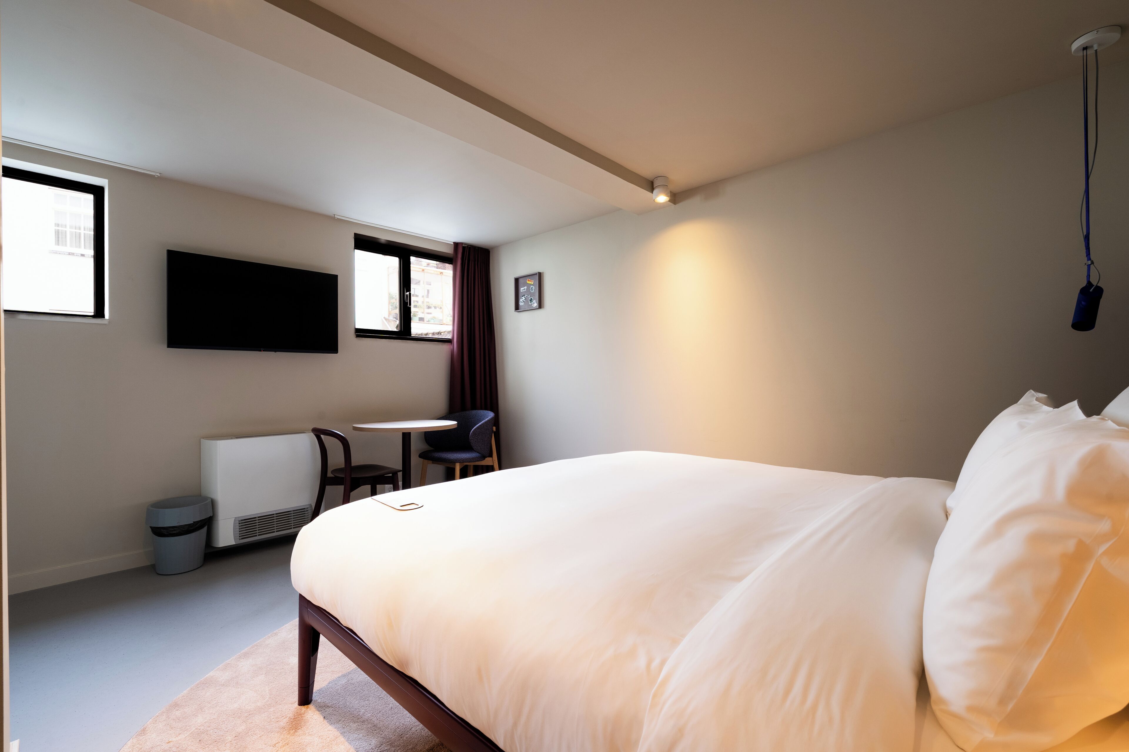 A modern bedroom with a large bed, a desk, and a chair.