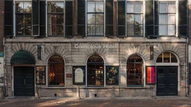 Egy történelmi épület, melynek számos ablaka és ajtaja van, és „Conscious Hotel” felirattal jelölték.