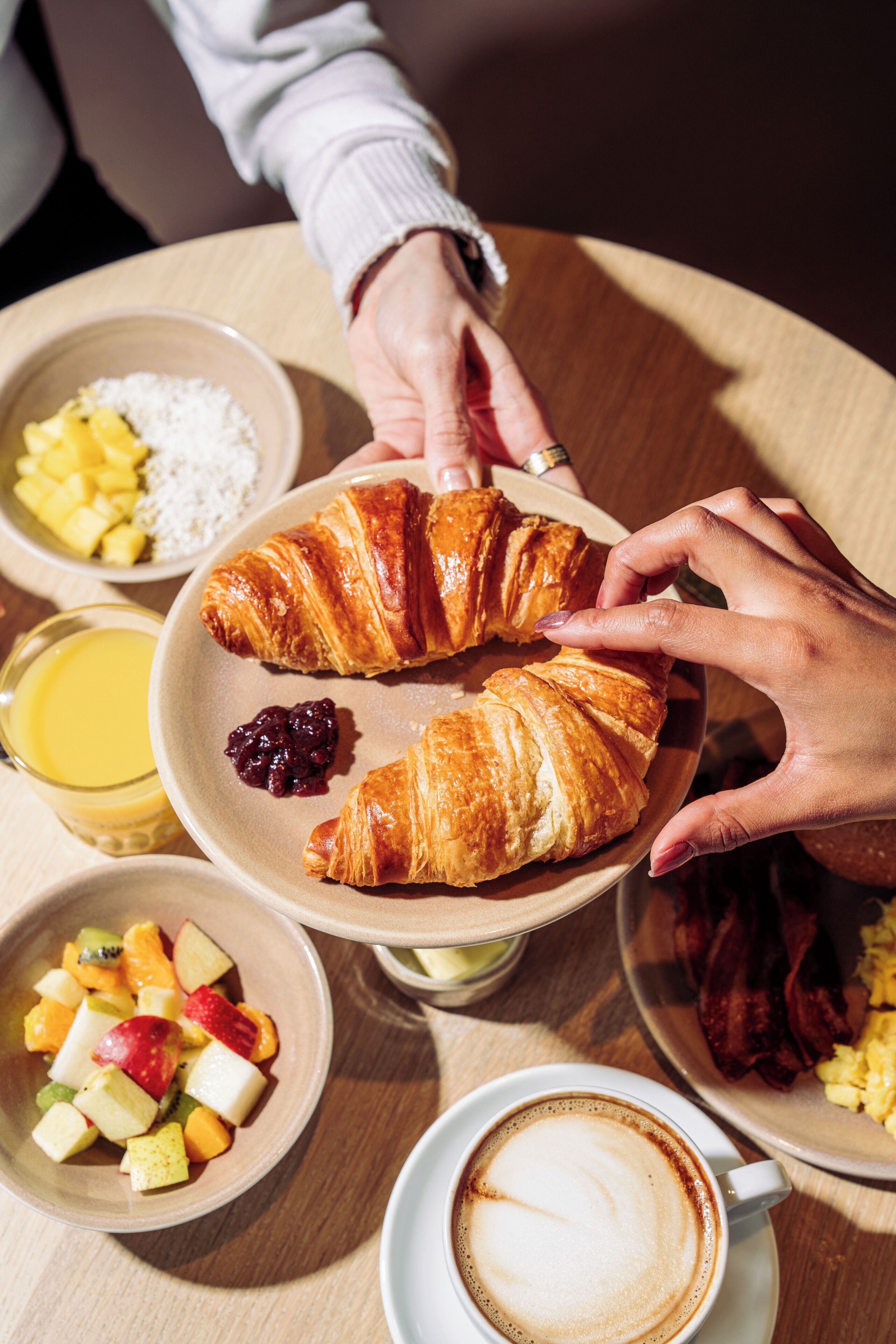 A breakfast setting with croissants, fruit, and coffee.