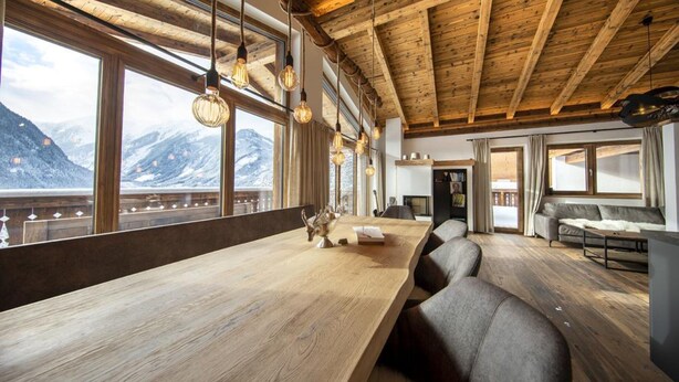 Un interno in legno con ampie finestre, un lungo tavolo e un divano.