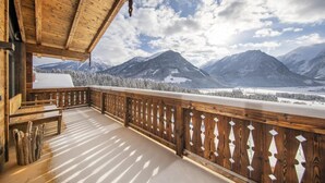 Un balcone in legno con vista su montagne innevate e un lago.