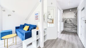A modern living room with a blue sofa, a yellow cushion, and a small table. - Apartamenty Sun & Snow Grunwaldzka (Pobierowo)