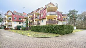 A multi-story residential building with balconies, a paved driveway, and a well-maintained hedge. - Apartamenty Sun & Snow Grunwaldzka (Pobierowo)