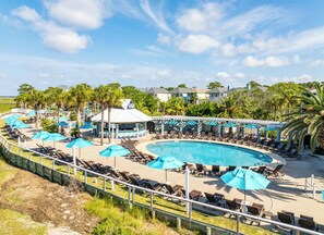 Relax by the resort pool surrounded by lounge chairs and tropical vegetation.
