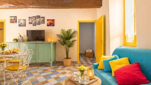 A cozy living room with a checkered floor, a blue sofa with colorful cushions, a dining area with a table and chairs, a television, and a potted plant. - 2 bedroom private vacation home in san feliciano, magione, perugia (San Feliciano, magione, Perugia)