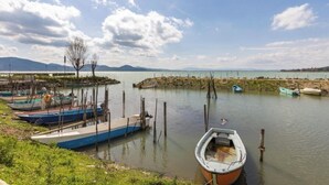 A calm water body with boats docked, a clear sky, and distant mountains. - 2 bedroom private vacation home in san feliciano, magione, perugia (San Feliciano, magione, Perugia)