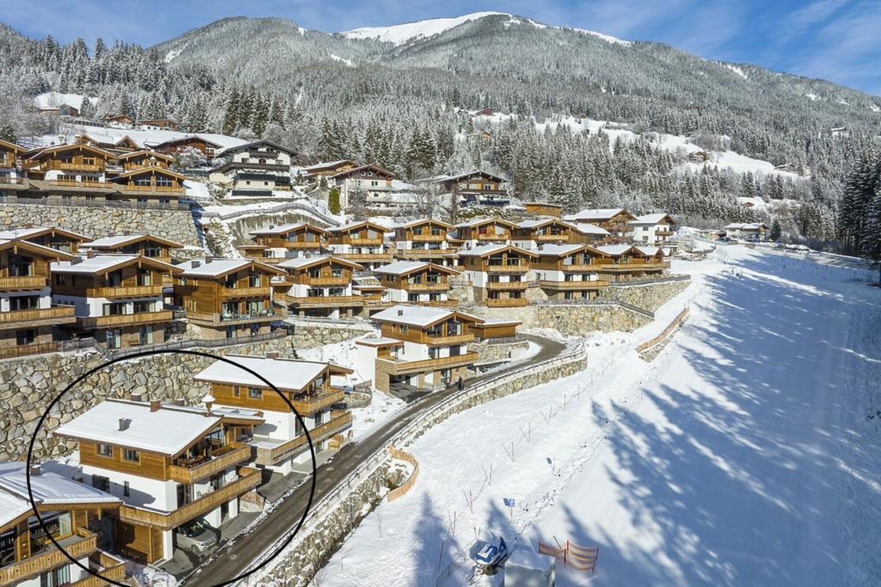A snow-covered mountain resort with wooden chalets and a winding road.