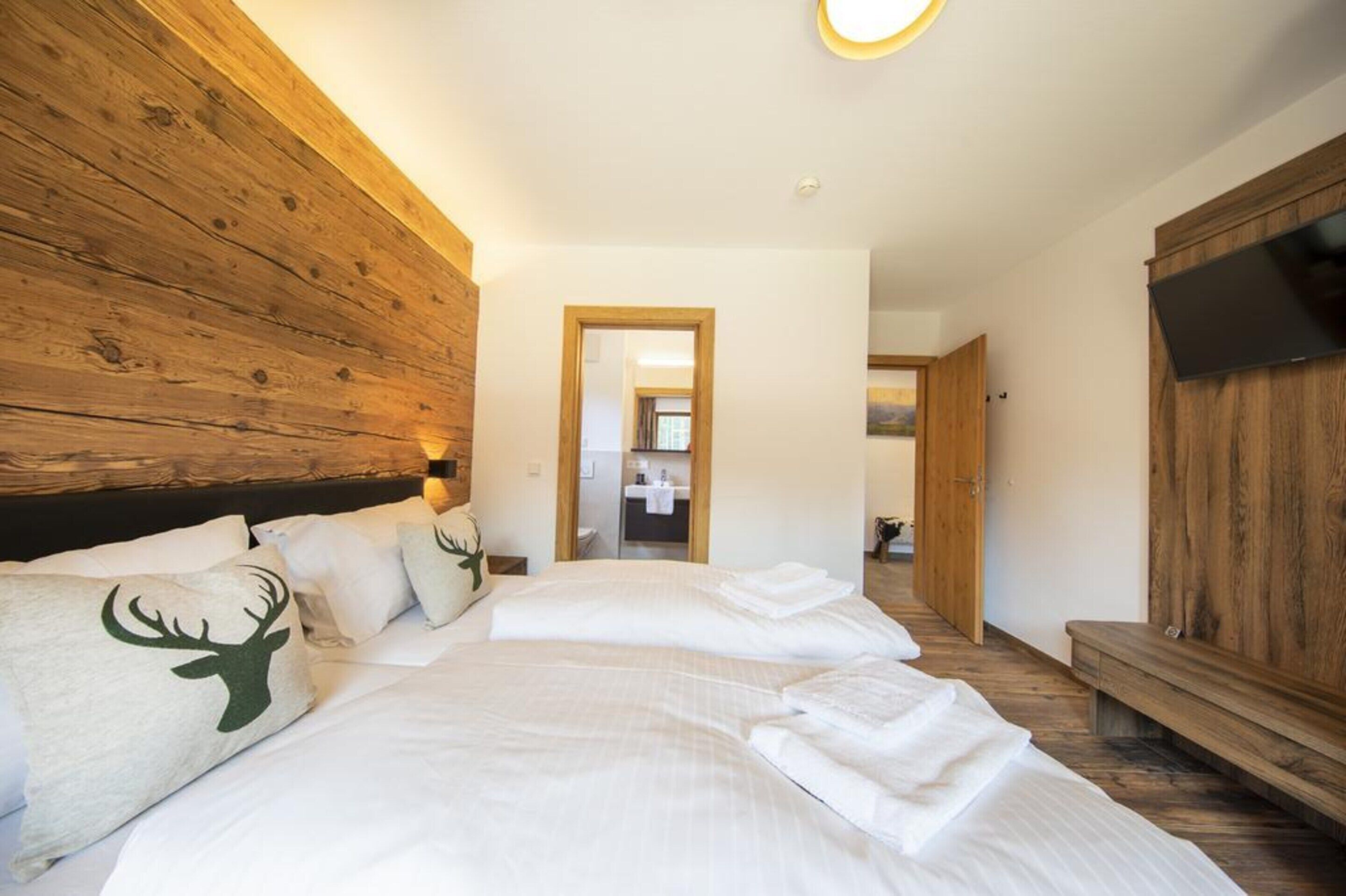 Una camera da letto con un letto grande, una testiera in legno e una televisione a parete.