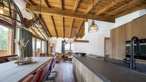 Una cocina amplia con vigas de madera, una larga mesa de comedor con bancos y una isla moderna con pileta y cocina.