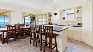 Una cocina amplia con una isla grande, sillas de madera y vistas al océano.