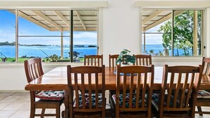 Un comedor con vistas al mar, sillas de madera y una mesa.
