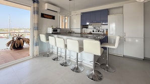 A modern kitchen with a bar area, white cabinets, and a view of the city. - Agi Cap Trencat 146 Apartamento for rent in Roses Girona. (Roses)
