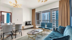 A modern living room with a sofa, chairs, a TV, and a balcony with a city view. - Bellavista-1BR-Full BurjKhalifa&Fountain (Dubai)