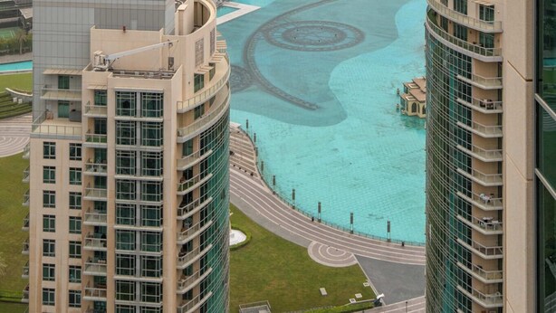 A high-rise building with a view of a large, circular water feature surrounded by other high-rise buildings. - Bellavista-1BR-Full BurjKhalifa&Fountain (Dubai)