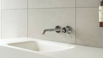 A modern bathroom with a white sink, chrome faucet, and a mirror above it.