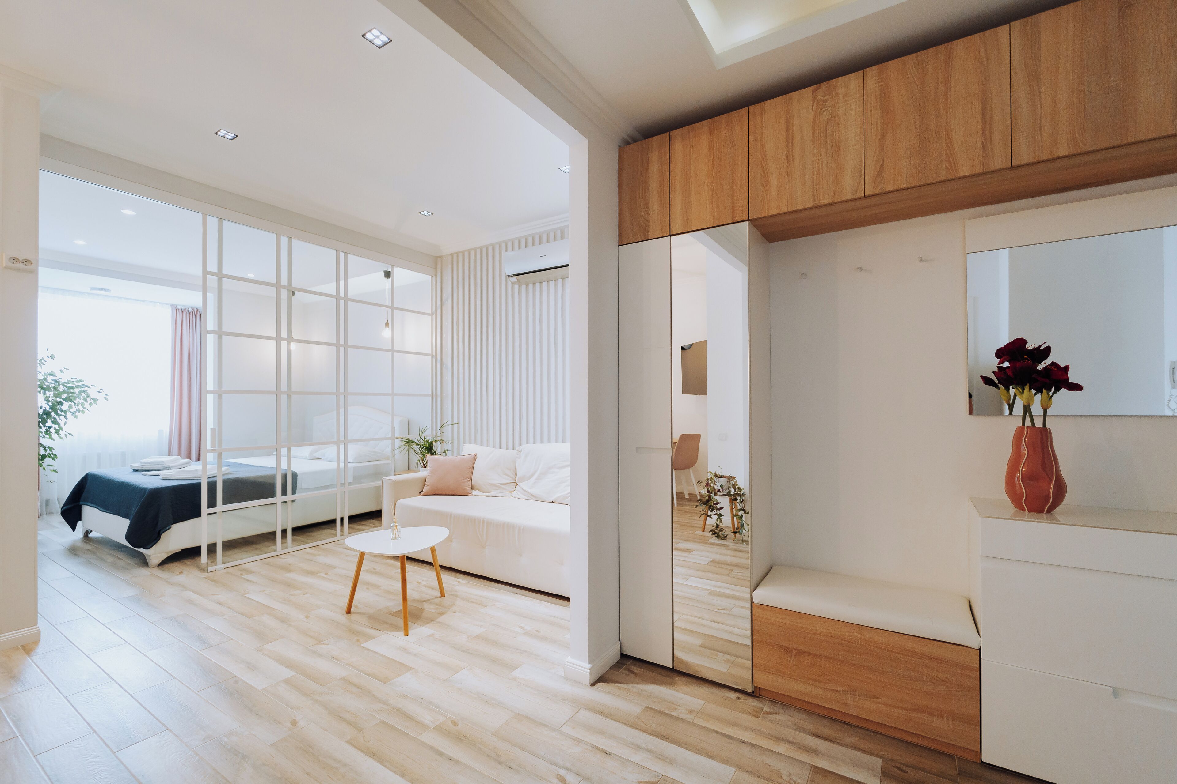 A modern hotel room with a large bed, a sitting area with a small table, and a wooden cabinet.