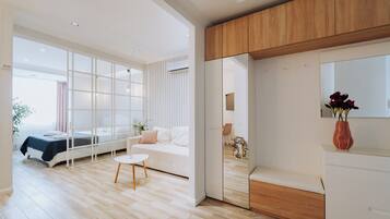 A modern hotel room with a large bed, a sitting area with a small table, and a wooden cabinet.