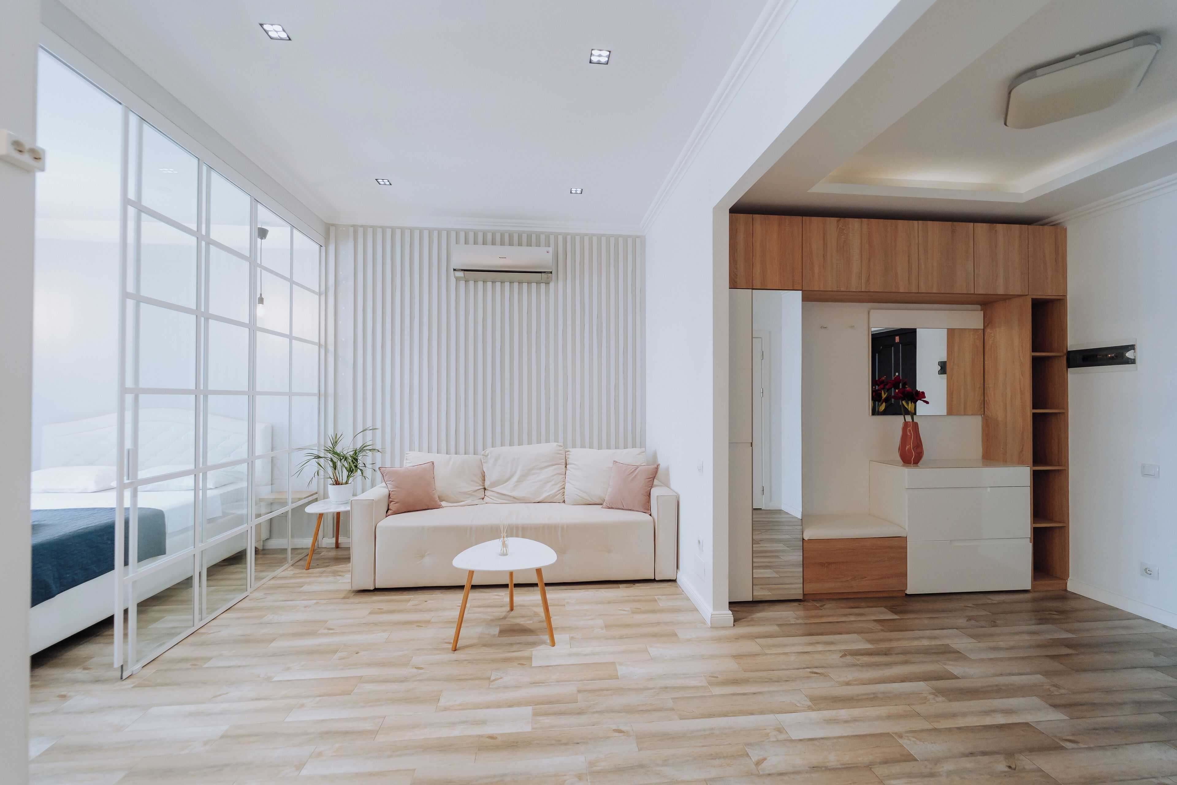 Una sala de estar moderna con un ventanal grande, un sofá, una mesita y un mueble de madera empotrado.
