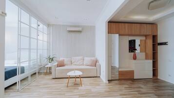 Una sala de estar moderna con un ventanal grande, un sofá, una mesita y un mueble de madera empotrado.