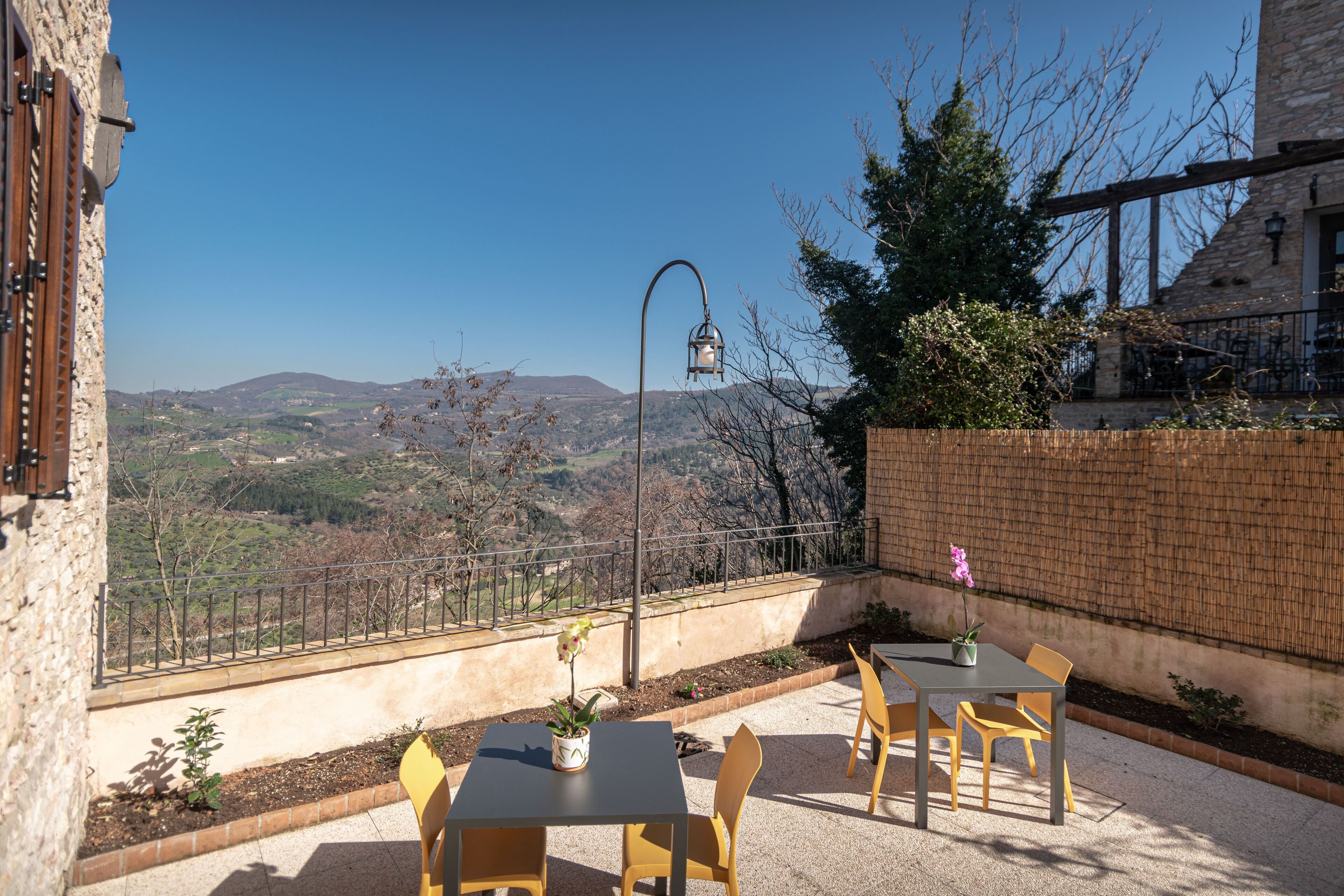 A patio with a table and chairs, a potted plant, and a view of the countryside.