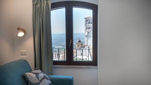 Een kamer met een gebogen raam met uitzicht op een historische toren en een stadsgezicht.