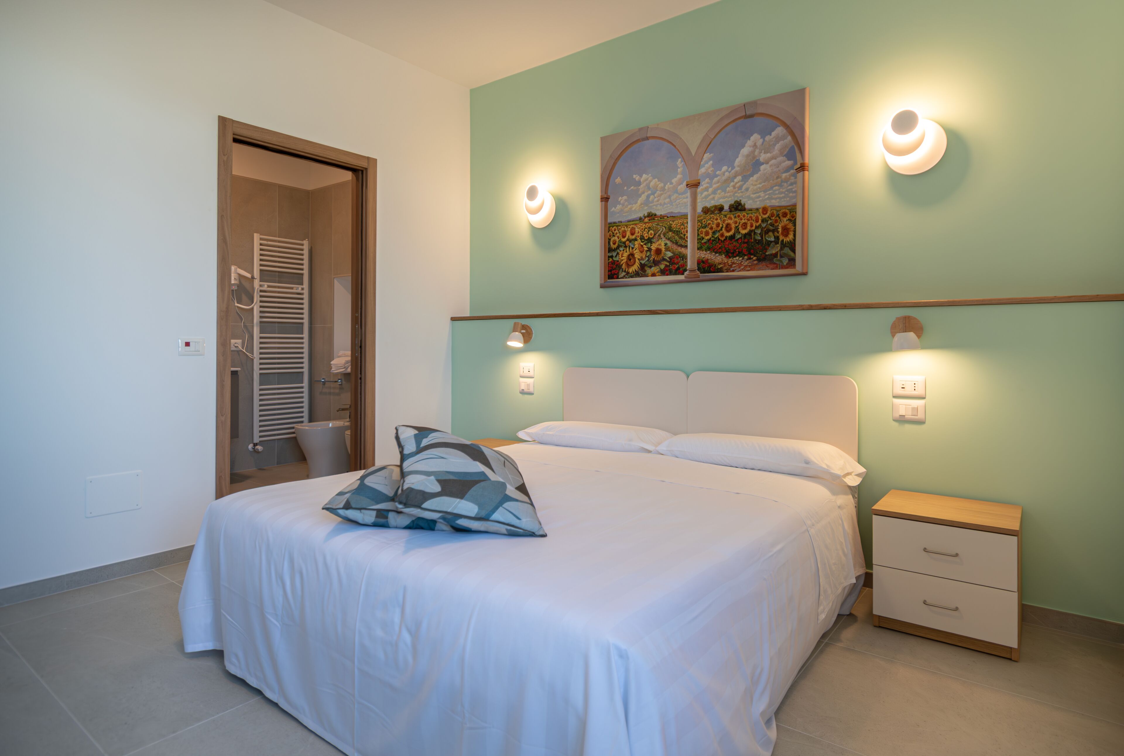 Um quarto com uma cama, mesas de cabeceira e um quadro na parede.