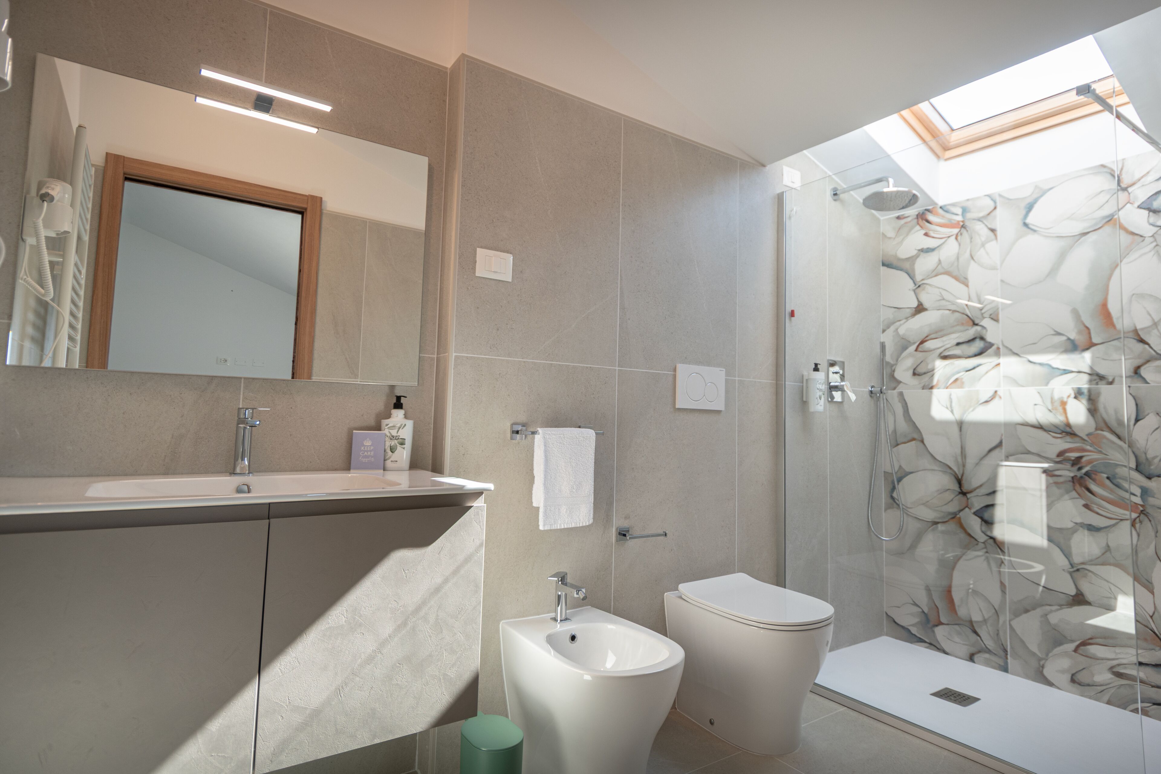 Un baño moderno con ducha, bidé y un espejo grande.