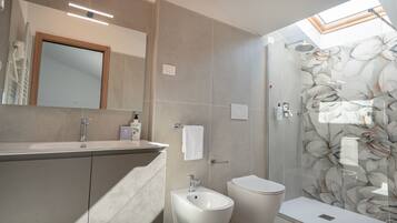 Un baño moderno con ducha, bidé y un espejo grande.