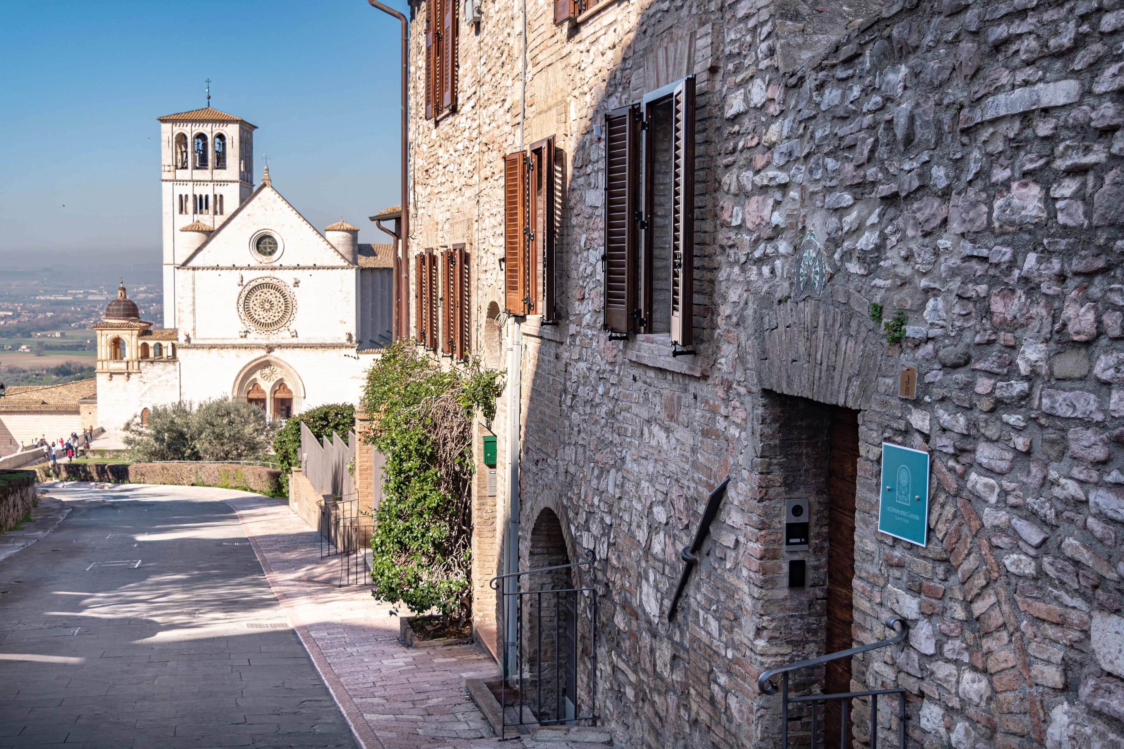 Un edificio in pietra con un campanile, una stretta via e un cartello che indica un sito storico.