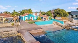 Une station balnéaire dotée d’une piscine à eau cristalline, de promenades en bois et de bâtiments aux couleurs turquoise.
