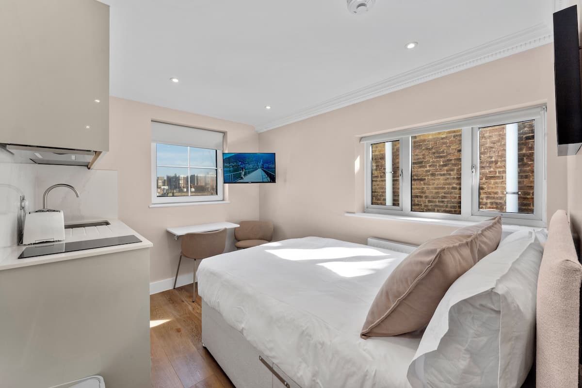 A modern bedroom with a bed, a desk, and a television.