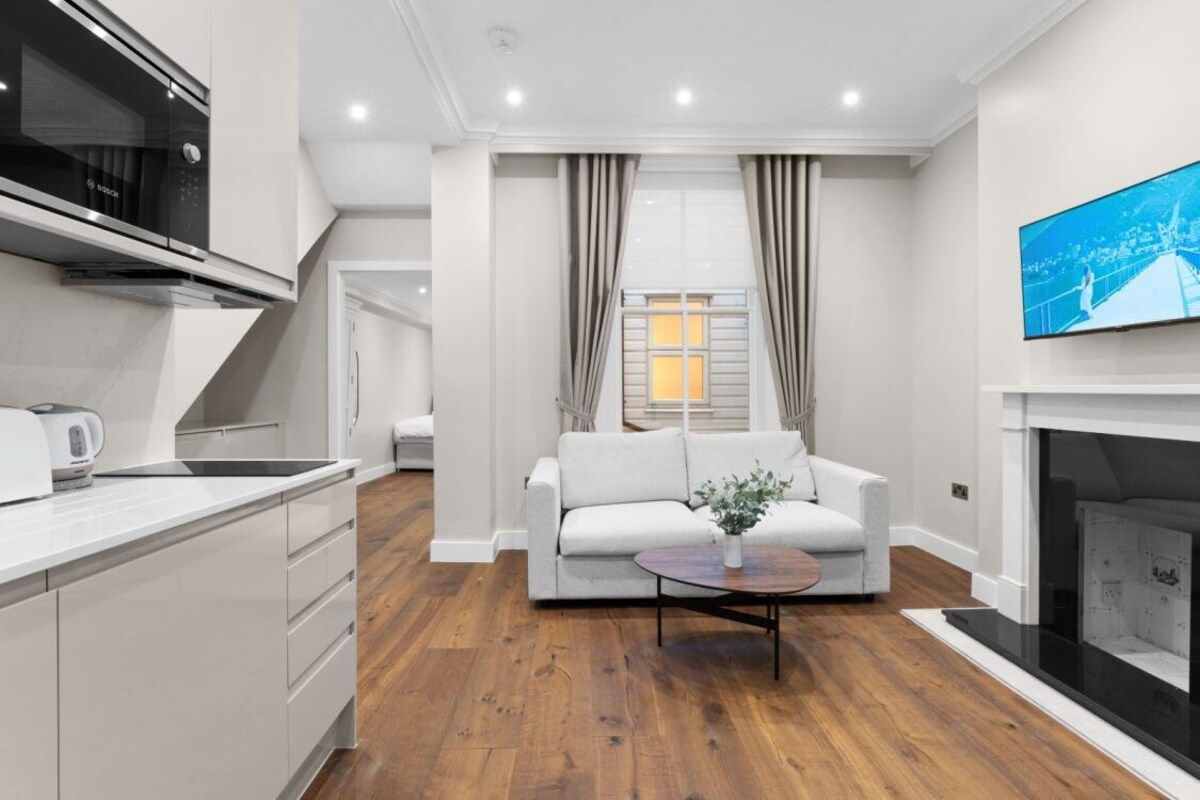 A modern living room with a sofa, coffee table, and a flat-screen TV mounted on the wall.