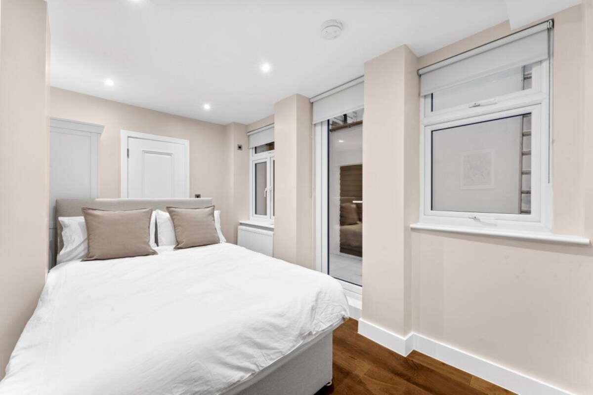 A bedroom with a bed, two doors, and a window.