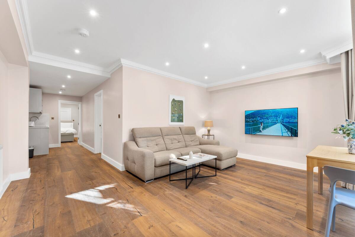 A modern living room with a sofa, coffee table, and a TV on the wall.
