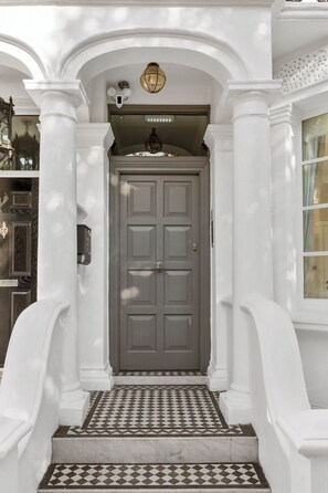 A grand entrance with a grey door, white columns, and a checkered tile floor. - Grove Heights Notting Hill (London)